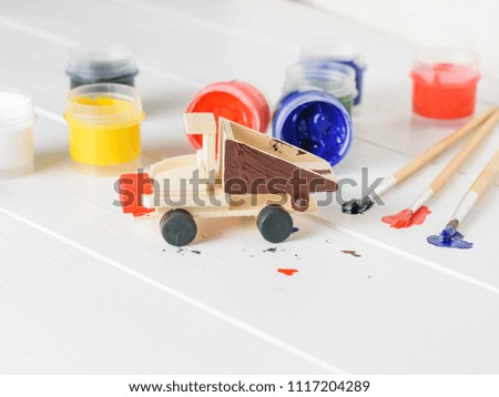 The process of decorating a wooden truck toy on a white table.