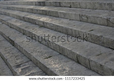 Close up outdoor perspective view of an ancient stone staircase. Pattern of long grey steps. Geometric image with oblique lines. Abstract architectural image and graphic design. 