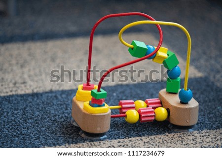 Wooden and metal toy for toddlers with small geometric objects on wires. Used for development of small motor skills in kids.