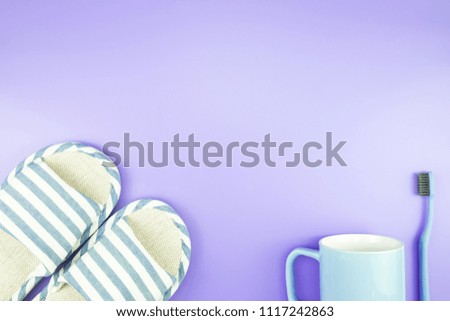 home equipment clock flat lay composition tooth brush glasses, towel and slippers top view on blue and purple violet concept