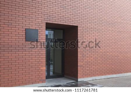 Entrance with a glass door to the modern office center. Loft style, red brick and laconic black sign at the entrance