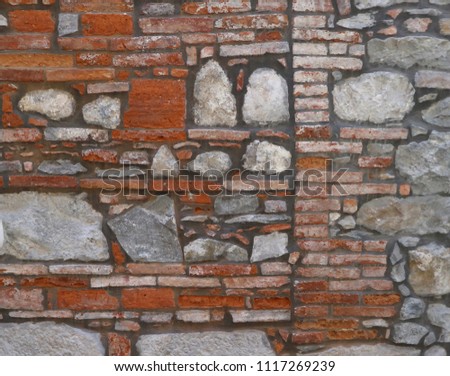 Ancient brick wall with large stone blocks inserted. Background and texture.