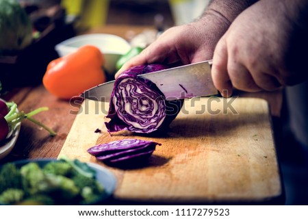 Closeup of hand with knife cutting red cabbage