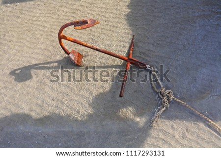 
Rust anchor in the sea sand at low tide