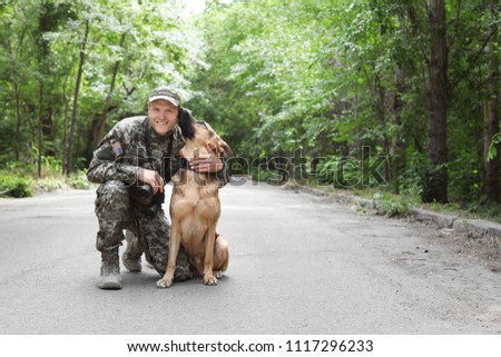 Man in military uniform with German shepherd dog, outdoors