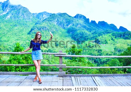 Asian girl holding a mobile to take a picture with Mountain view in the winter of Thailand at Ban rabiang dao homestay, Doi Luang Chiang Dao, Fang, Chiang Mai, Thailand