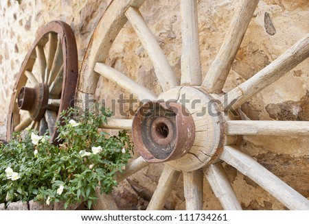 Wooden wheel. Antique and beautiful wooden wheels leans against ancient stoned wall
