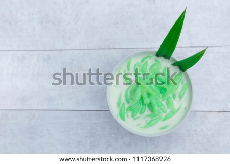 Top view food.Pandan Noodles with Coconut Milk.Lod Chong in Coconut milk Thai Dessert in bowl and white table.Decorated dessert with Pandan leaf.
