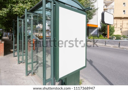 White vertical billboard in the bus stop by the street in the city