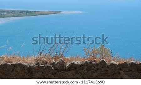 view of the blue sea from the mountain, an old wall overgrown with grass