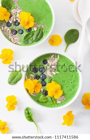 green spinach smoothie bowl with blueberry, chia seed and edible pansy flowers