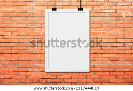 White poster Or a white frame hanging on the brick wall background in the room.