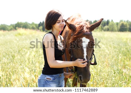 
A girl and a horse are walking in a field of wheat.