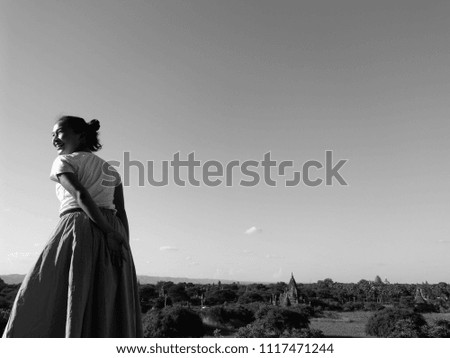 Young Asian woman taking photo with landscape view of scenic sunrise above Bagan in Myanmar (Burma). Bagan is an ancient city with thousands of historic buddhist temples and stupas.