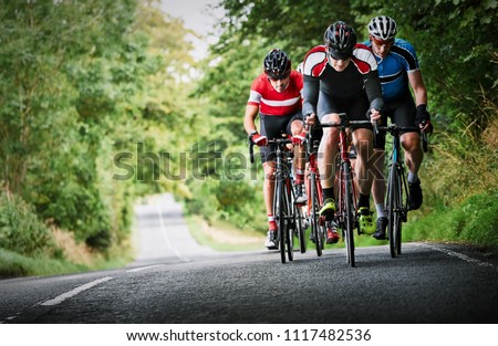 Cyclists racing on country roads on a sunny day in the UK. Royalty-Free Stock Photo #1117482536