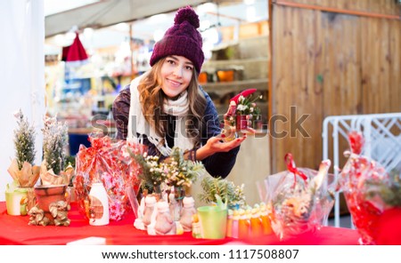 Pretty young teenager girl buying floral compositions at Christmas market