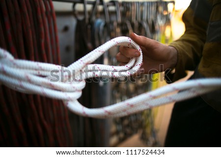 
Picture of male hand inspector inspecting, daisy chain knot on brand new industrial rope access static low stretch 10.5 mm abseiling working at height life safety equipment with blurry background 