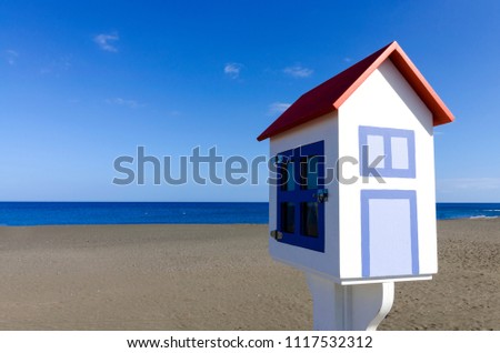 A miniature model of a house with a dark volcanic beach and a blue sky in the background