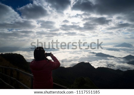 Silhouette Women taking photo with smart phone at mountain,take photos in front of fog beautiful.