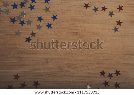 Confetti stars on wooden background. 4th July, Independence day, card, invitation in usa flag colors. Top view, empty space. Toned.