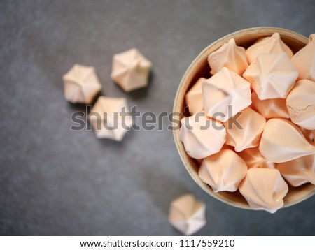 Colorful meringue cookies, some placed in a bowl and some scattered, top view