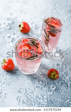 Alcoholic or non-alcoholic cocktail with strawberries and rosemary and ice in glass glasses