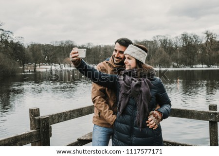 Sweet lovely couple visiting Sweden. Walking around on a cold spring morning near to a beautiful lake with a wooden dock. Lifestyle.