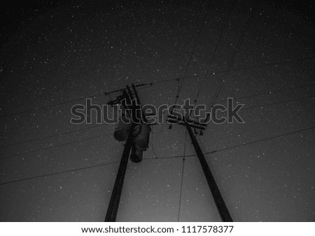 Black and white shot of a Transformer and transmission lines with lots of stars in the background