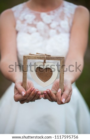 Bride holding a wooden heart shape frame for a picture. 