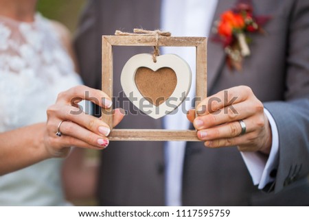 Bride holding a wooden heart shape frame for a picture. 