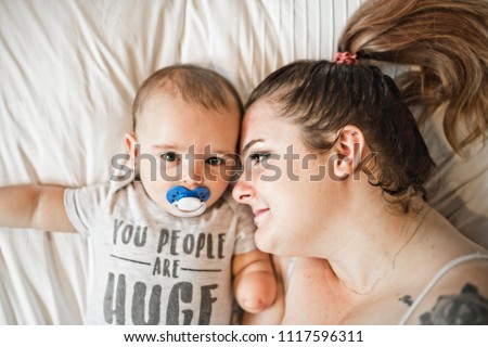 Portrait of beautiful mom playing with her 8 months old baby in bedroom, top view