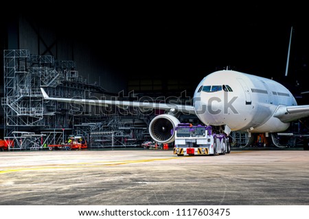 Aircraft towing tractors towing aircraft (airplane) out from aircraft hangar after finished maintenance. Royalty-Free Stock Photo #1117603475