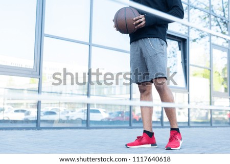 cropped shot of african american sportsman holding basketball ball on street