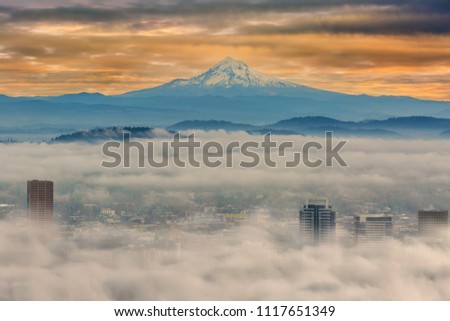 Rolling fog over the city of Portland Oregon downtown cityscape with Mount Hood during early morning sunrise