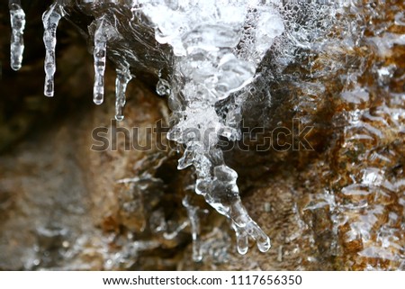 The icicles thawing on a stone wall in the mountains of France in the winter