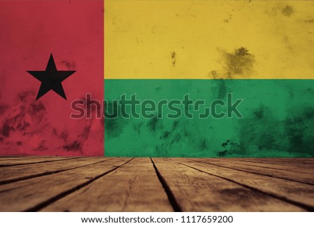 The floor of planks and plastered wall with a painted  Guinea Bissau  flag.