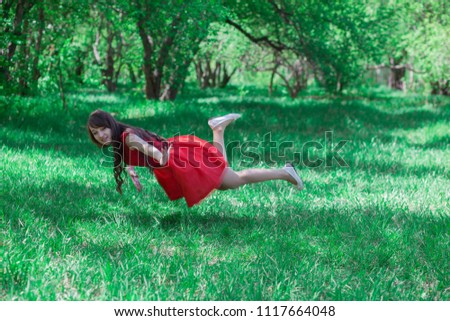 beautiful girl in a red dress among the green grass. levitation. photo for your design