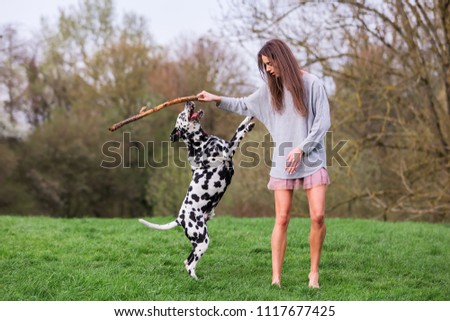 picture of a young woman who plays with Dalmatian dog outdoors