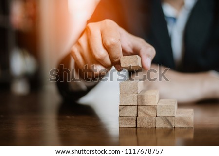 plan and strategy in business.risk concept.hand of man has piling up and stacking a wooden block.Businessman Building The Success. Royalty-Free Stock Photo #1117678757