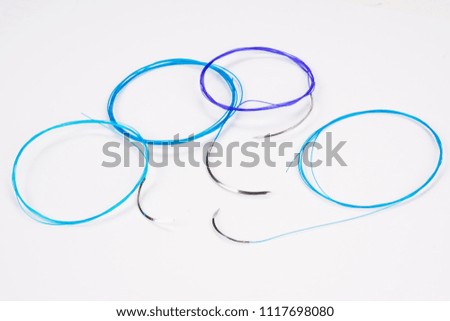 Colorful surgical nylon monofilament suture with curved needle isolated on an abstract blurred white background. Healthcare, medical and surgery concept. Detailed close up with soft selective focus