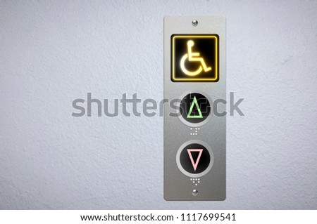 Elevator buttons panel with an amber glowing light button for handicap and Braille code for the visually impaired.