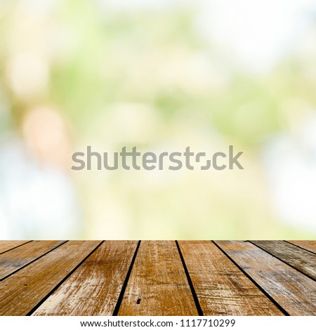 blur soft green nature background with glow sunny light and aged plain wood table top perspective view for promote or present product concept.