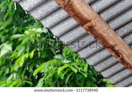 rain drops fast dipping from old zinc roof with blur nature background