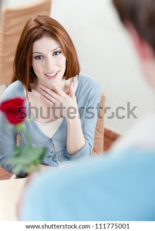 Man presents a crimson rose to his girlfriend at the coffee house