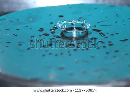 Water drop photography with stunning aqua and silver background ,crown shape splashing around the water forming bubbles