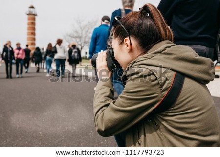 A professional street photographer or young tourist woman makes photos on the street where many people in Lisbon