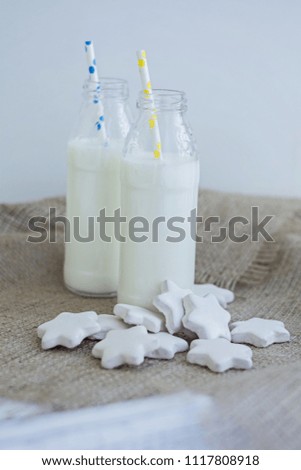 Bottle of milk and cookies shaped stars on white wooden table