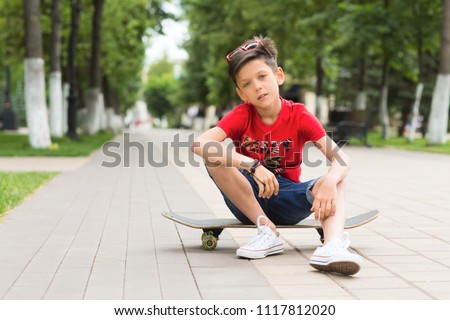 Happy smiling stylish teen boy with a skateboard in outdoors. Concept lifestyle and sportive life. 
