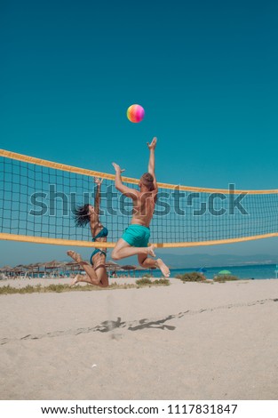 Couple have fun playing volleyball. Young sporty active couple beat off volley ball, play game on summer day. Woman and man fit, strong, healthy, doing sport on beach. Beach volleyball concept.