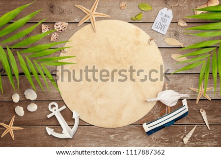 Old round paper on rustic wooden background surrounded with summer holiday decoration. Palm leaves, seashells, anchor, starfish and boat. Empty space for text, travel concept